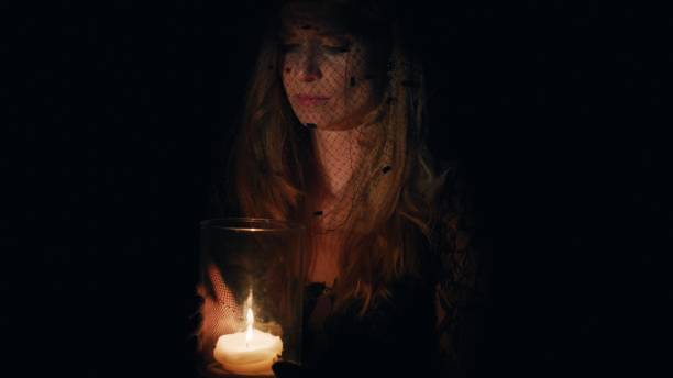 istock A woman blows out a candle. Dressed in mourning clothes. 1651266850