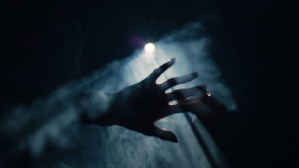 Silhouettes of two hands reaching for each other, a close up.