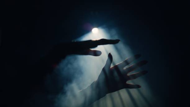istock Hands outstretched towards the beam of light from the spotlight. 1651267406