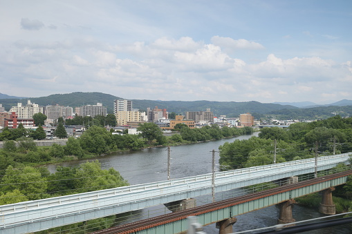 High angle view looking east. Elevated train tracks cross over the Shizukuishi River near the Kitakami River.