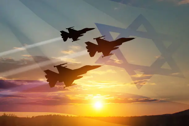 Photo of Aircraft silhouettes on background of sunset with a transparent waving Israel flag. Military aircraft.