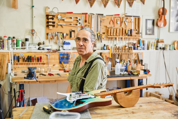 istock Portrait of a smiling luthier man in his workshop looking at the camera. 1651309878