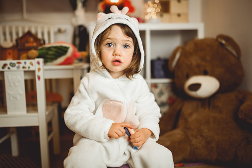 portrait of a toddler girl in a cosy pajamas in a domestic room.