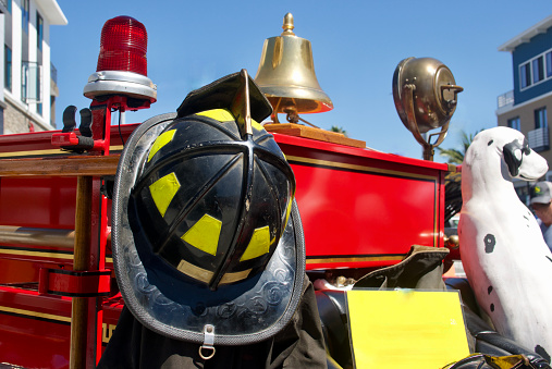 Outdoor portrait of diverse female and male firefighters posing in front of the fire engine, looking at the camera, holding their helmets.