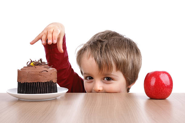 istock Small boy choosing to eat cake instead of an apple  165137892