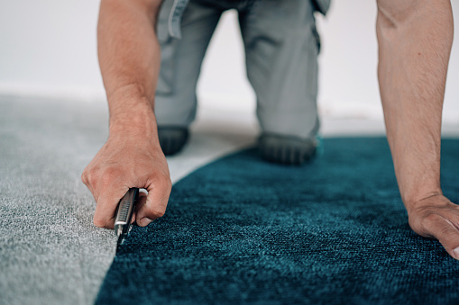 Giving a makeover to the business interior, a young man installs carpets, elevating the aesthetics and comfort