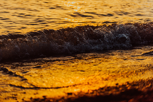 A vibrant orange sunset paints the tranquil ocean waves, casting a serene and captivating atmosphere over the pristine beach.