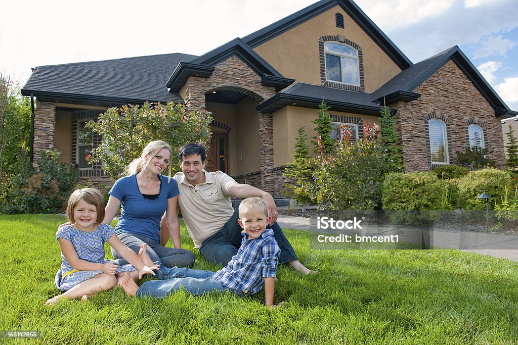 Sonriendo familia en jardín delantero de una casa - Foto de stock de Familia libre de derechos