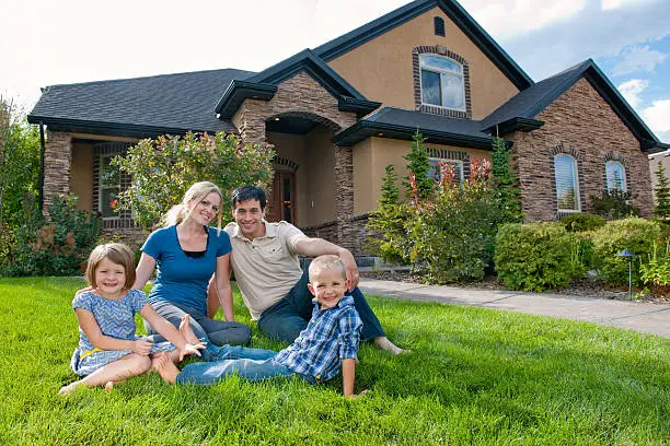 Photo of Smiling family on front lawn of a house