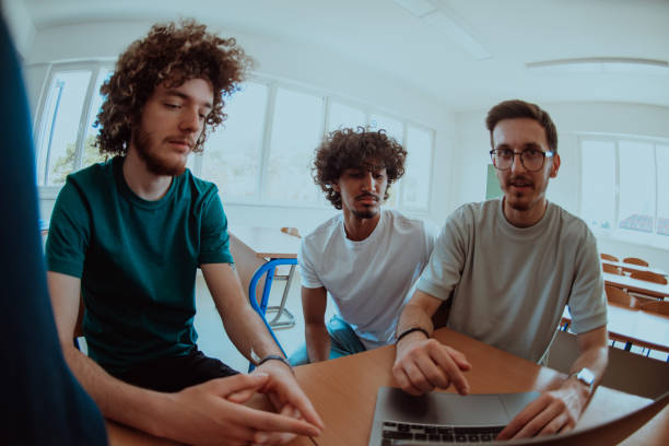 istock A diverse studetns group, including an Afro American with an afro hairstyle communicating and engage with their colleague while seated in a modern classroom, collectively focused on a laptop. 1651429764