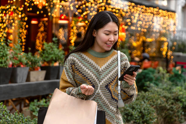Young woman with Christmas presents using mobile banking