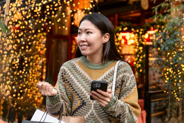 istock Beautiful woman using mobile phone during shopping in wintertime 1651463739