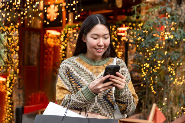 istock Young woman with Christmas presents using mobile banking 1651464257
