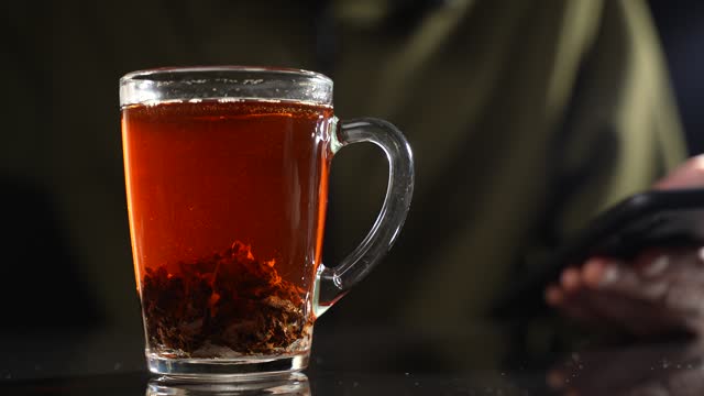 Pour sugar into tea in a glass mug. Slow motion