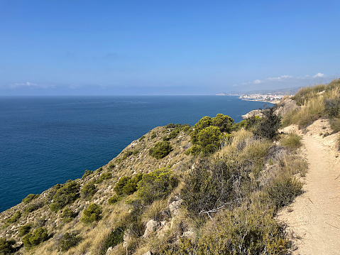 Landscape of cliff by the seaside. La Vila Joiosa in the background. Villajoyosa, Alicante, Spain. Summer vacational destination. Travel concept. High quality photo