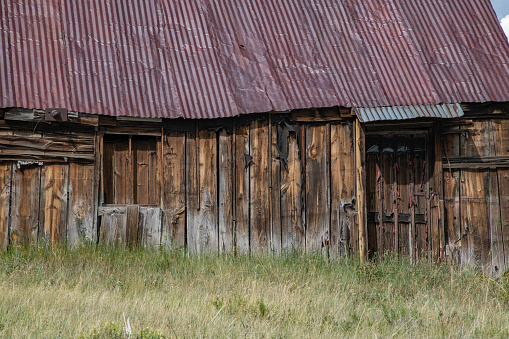 An abandoned old barn with the symbol of Texas painted on the roof sits in a rural area of the state, framed by farmland.