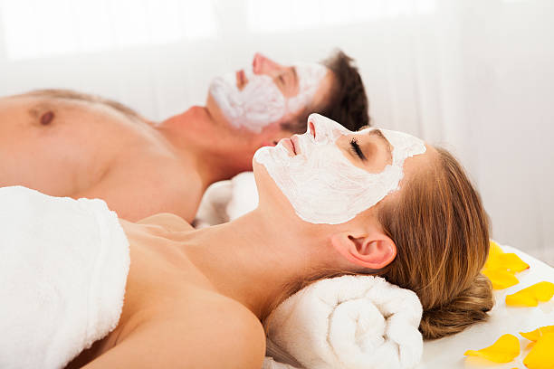 uomo e donna in maschere per il viso - spa treatment health spa massaging couple foto e immagini stock