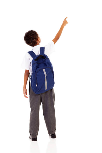 little schoolboy with schoolbag pointing little schoolboy with schoolbag pointing at empty copy space elementary student pointing stock pictures, royalty-free photos & images