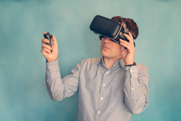 vr game and virtual reality. man gamer fun playing on futuristic simulation video shooting explore game in 3d glasses and joysticks on a blue background.