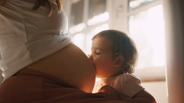 SLO MO Smiling Cute Girl Kissing and Listening to Pregnant Belly of Mother at Home