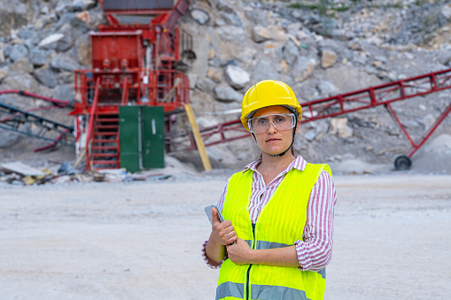 Woman construction worker, builder, architect in red protective uniform holding in hands white helmet on white background with empty copy space for inscription . Safety concept.