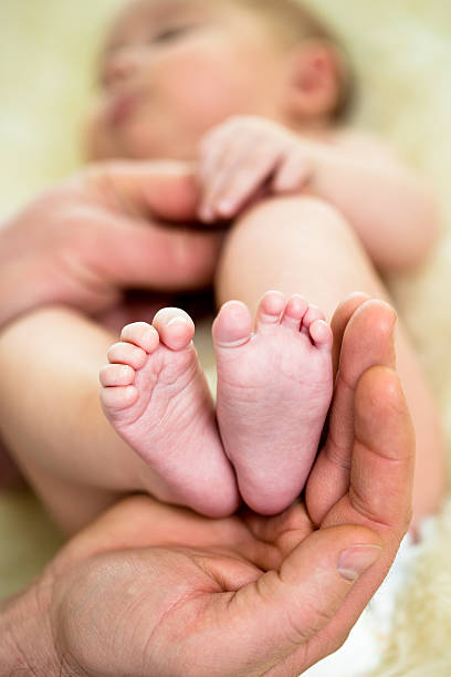 istock father hand holding small baby's feet 165167429
