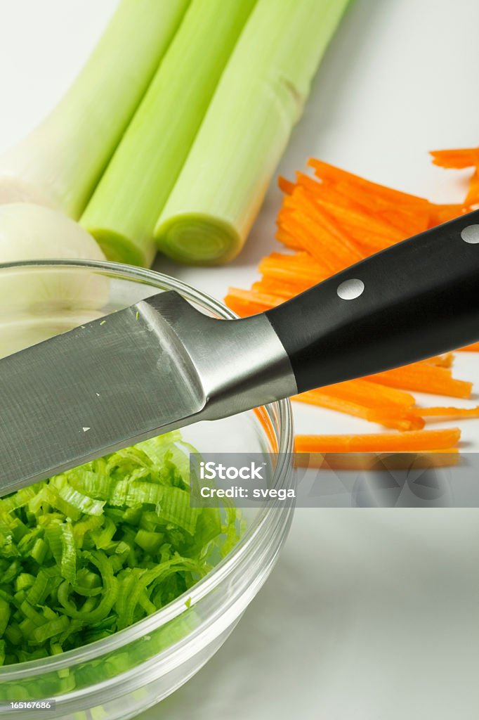 Кухонный нож в миску с нарезанный лук-порей - Стоковые фото Белый фон роялти-фри