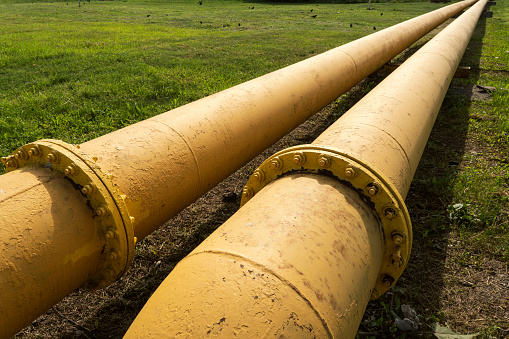 yellow gas pipeline that laid through green field. Gas delivery to remote regions. a long yellow pipe.