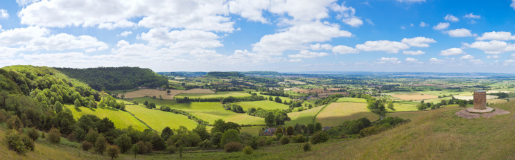 Sweeping panoramic view of the green and vibrant English countryside.  Farmland, rivers and villages pepper this impressive and unique landscape.  Hazy horizons and glorious greens in this summer scenic.  Stitched panorama.  