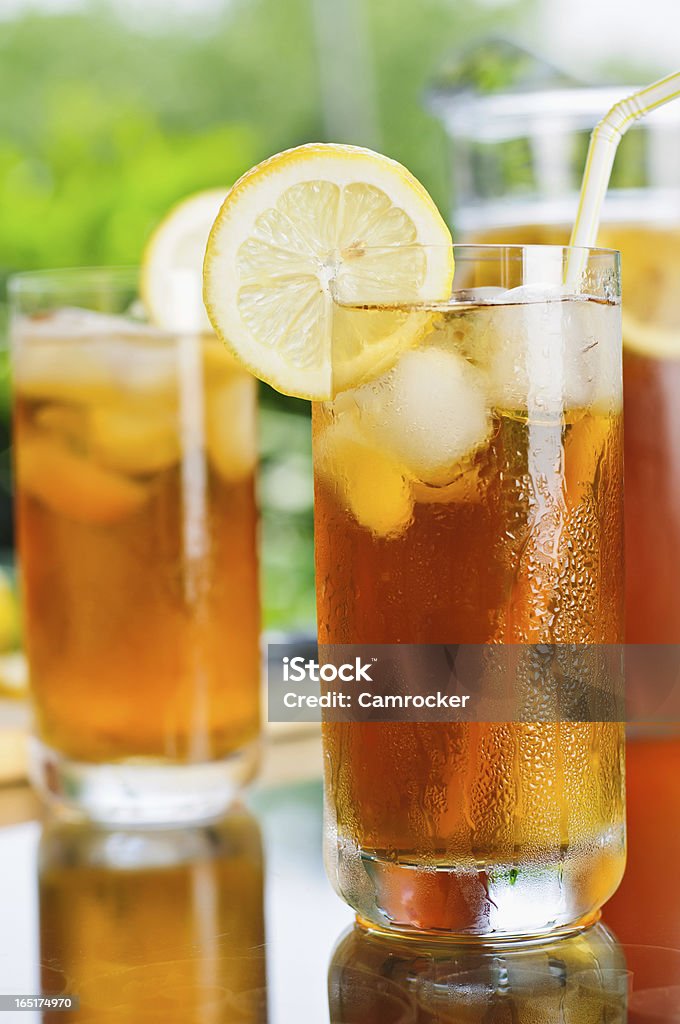 Ice Tea Outdoors Several glasses and a pitcher of ice tea on a patio glass table. Color Image Stock Photo