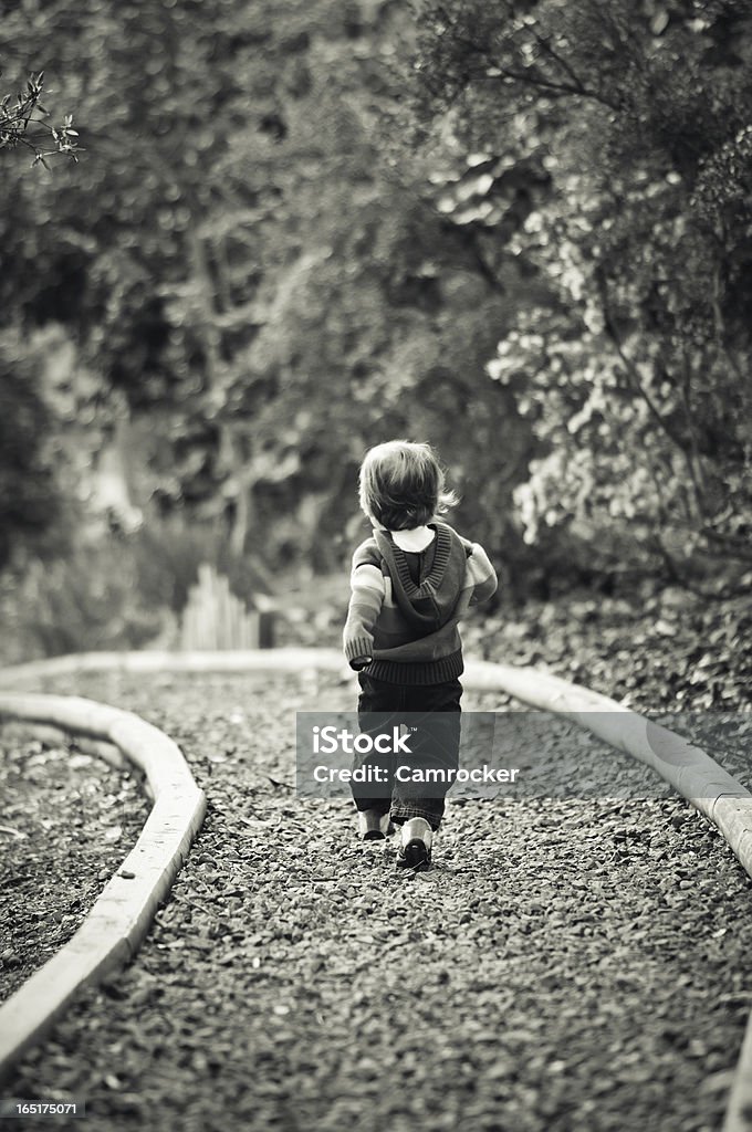 Toddler Walking On Path A young boy walks along a gravel path with an optimistic spring in his step. Boys Stock Photo