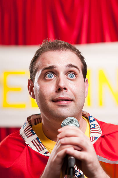 Spelling Bee Contestant Adult man pretending to be a kid in a spelling bee, looking very nervous, clutching the microphone and sweating. spelling bee stock pictures, royalty-free photos & images