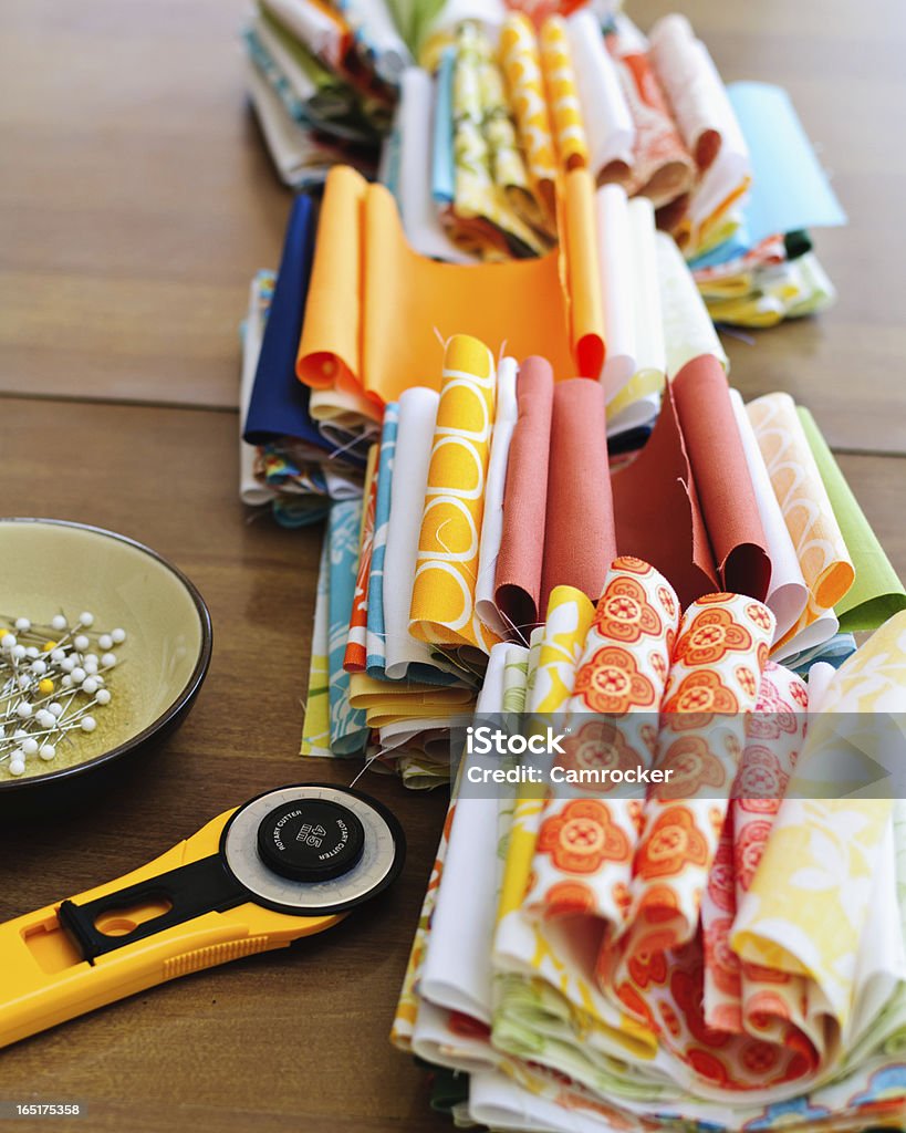 Quilting Fabrics and Tools Many different fabrics for a quilt and a rotary cutter and pins. Abstract Stock Photo