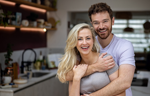 Portrait of a loving Caucasian couple at home and looking at the camera smiling - domestic life concepts
