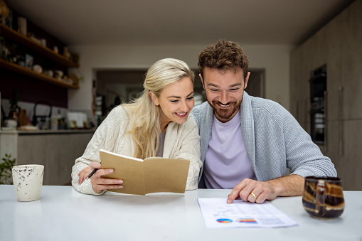 Happy couple looking at their home finances and looking excited about their investments - financial concepts
