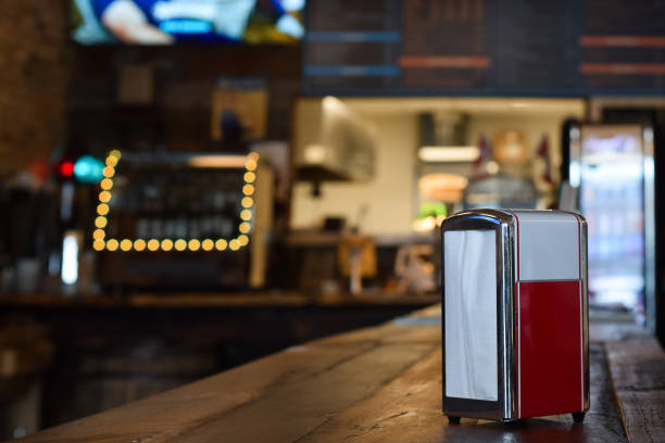 Retro style red and white napkin dispencer on a taple at a diner with defocused interior