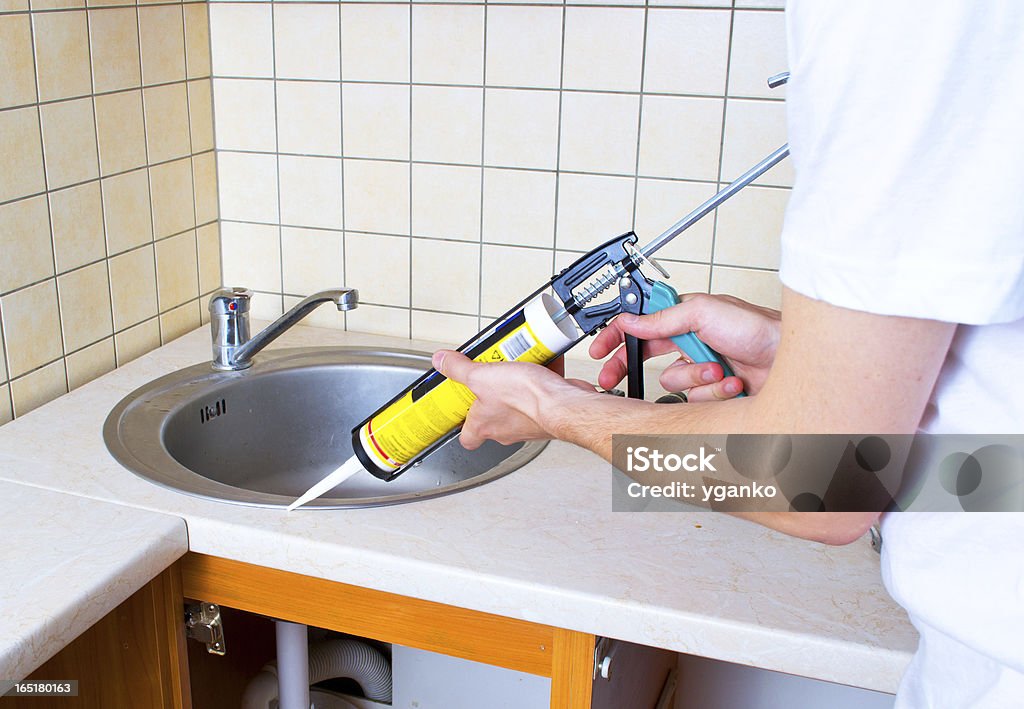 Caulking gun putting silicone sealant to installing a kitchen sink Silicone Stock Photo