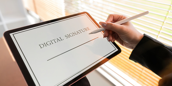 Close up businessman hand electronic signature on tablet write business agreement of contract technology concept.