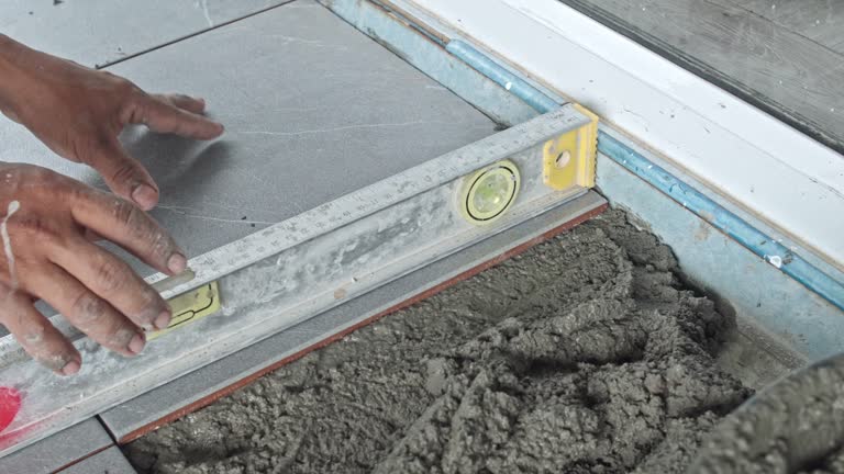 Preparation of tiling on liquid cement on construction site, home improvement service industry concept.