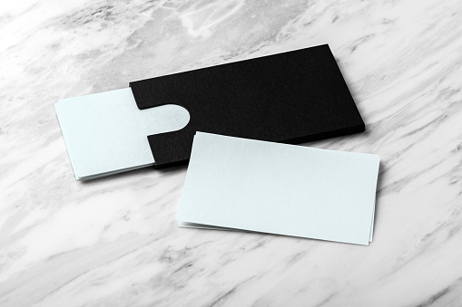 Pastel blue business card with black paper card holder on white marble background