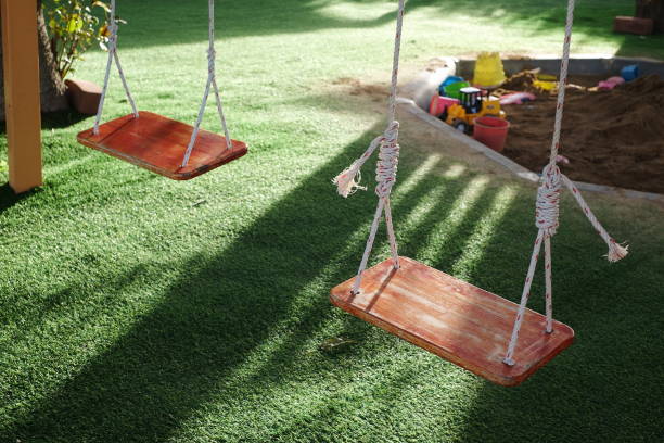Two empty wooden swing with sunlight in playground.