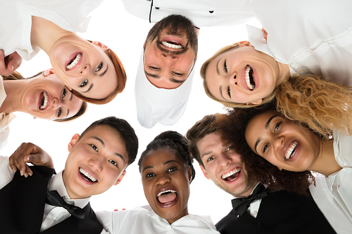 Low Angle View Of Happy Restaurant Staff Standing Against White Background