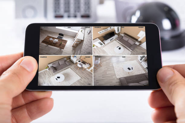 istock Person Holding Mobile Phone With CCTV Camera Footage On Screen 1652006003