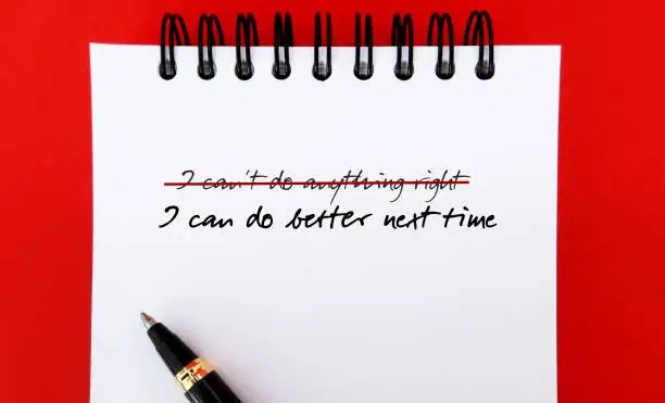 Handwritten text on notebook I CAN'T DO ANYTHING RIGHT, replaced with I CAN DO BETTER NEXT TIME - to challenge pessimistic self-talk by reframe negative thoughts to positive thinking and increase self-confidence