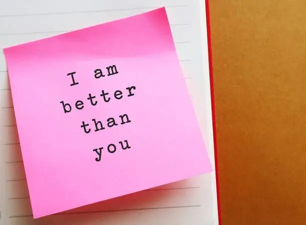 Photo of Pink note on envelope background with handwritten text SUPERIORITY COMPLEX, means belief that your abilities or accomplishments are dramatically better than someone else