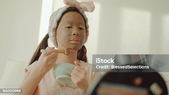 istock Happy mixed Asian preteen girl applying clay facial mask at home, skincare routine, self care and wellness concept 1652013088