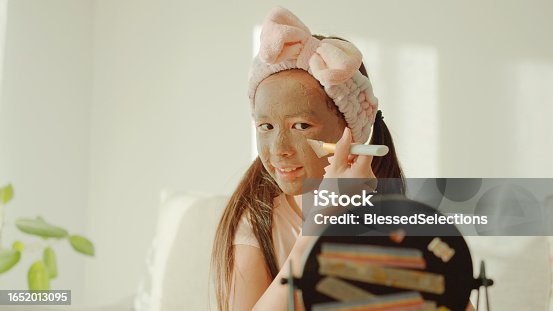 istock Happy mixed Asian preteen girl applying clay facial mask at home, skincare routine, self care and wellness concept 1652013095