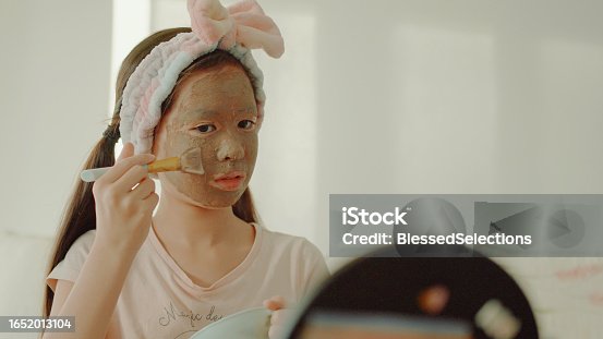 istock Happy mixed Asian preteen girl applying clay facial mask at home, skincare routine, self care and wellness concept 1652013104