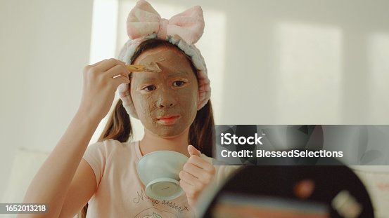 istock Happy mixed Asian preteen girl applying clay facial mask at home, skincare routine, self care and wellness concept 1652013218