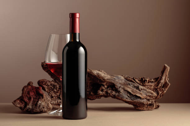 bouteille et verre de vin rouge avec un vieux chicot patiné sur un fond beige. - concepts wine wood alcohol photos et images de collection
